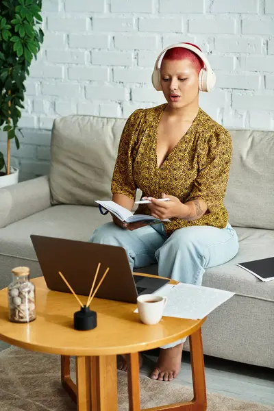 Eine schöne Frau mit Glatze schreibt nachdenklich in ihr Notizbuch, während sie sich zu Hause entspannt. — Stockfoto
