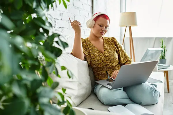 The beautiful bald woman with vibrant red highlights is immersed in creative work at home, smiling. — Stock Photo