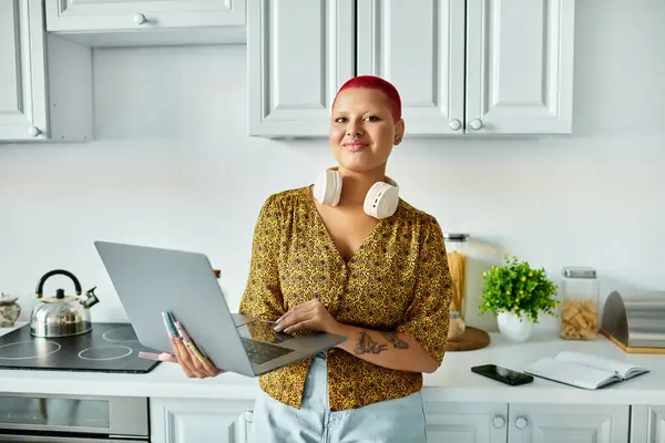 A stylish bald woman engages with her laptop in a cozy, contemporary kitchen space. — Stock Photo