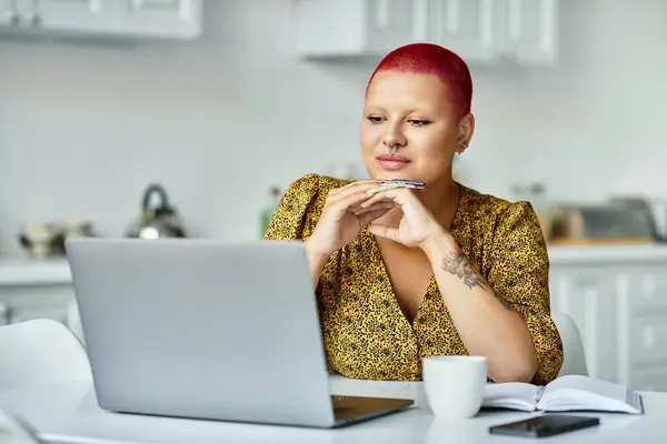 Una donna con una sorprendente acconciatura calva è impegnata in un profondo pensiero durante l'utilizzo del suo computer portatile. — Foto stock