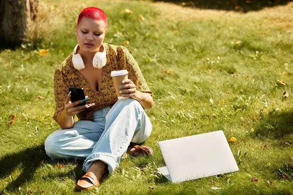 A bald woman with vibrant hair sips coffee while using her phone on a sunny day outdoors. — Stock Photo