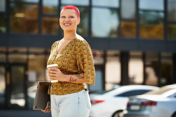 A bald woman with a joyful smile holds a coffee cup while standing near a modern building. — Stock Photo