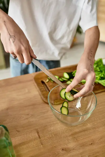 Um jovem habilmente fatias pepinos para uma salada saudável em uma cozinha contemporânea. — Fotografia de Stock