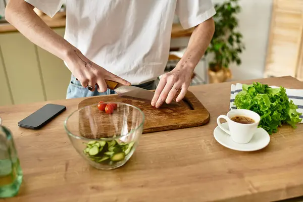 In a sleek modern kitchen, a handsome man skillfully prepares a healthy salad with fresh ingredients. — Stock Photo