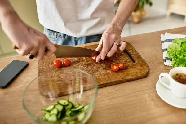 A handsome young man skillfully chops tomatoes while creating a vibrant salad in a stylish kitchen setting. — Stock Photo