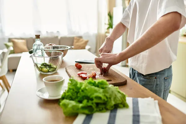 A handsome young man crafts a vibrant salad, showcasing fresh ingredients in a stylish kitchen setting. — Stock Photo
