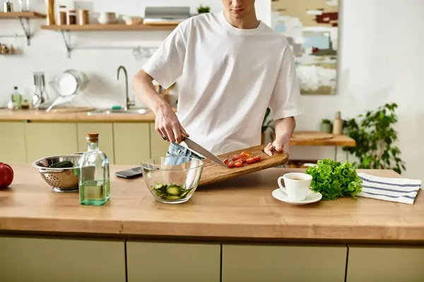 A young man skillfully chops vegetables while creating a vibrant salad in a chic kitchen setting. — Stock Photo