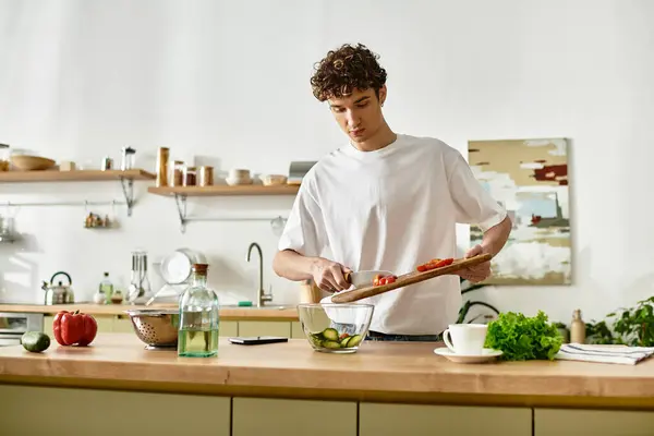 A handsome young man skillfully chops vegetables while making a vibrant salad in his contemporary kitchen. — Stock Photo