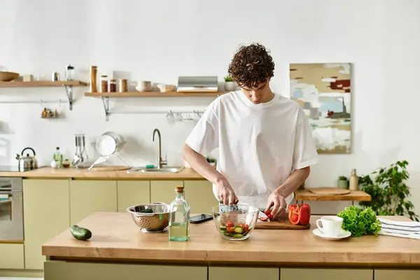 In a sleek kitchen, a handsome young man prepares a vibrant salad, embracing healthy living and culinary creativity. — Stock Photo