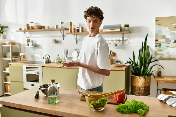 A handsome young man is crafting a vibrant salad in a sleek kitchen, embracing healthy eating habits. — Stock Photo