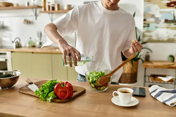 A handsome young man in a modern kitchen crafts a vibrant salad, embracing healthy eating habits with joy. — Stock Photo