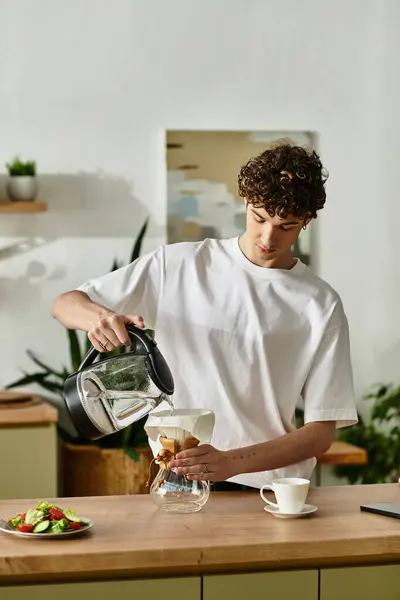 In einer sonnigen Küche brüht ein gelockter Mann gekonnt Kaffee, umgeben von lebendigen frischen Zutaten. — Stockfoto