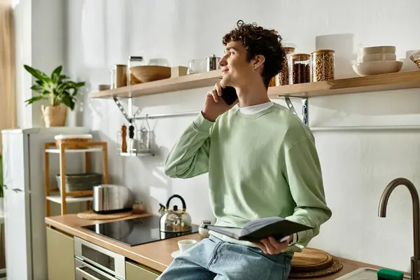 In a sleek kitchen, a handsome young man engages in conversation while exploring a recipe book. — Stock Photo