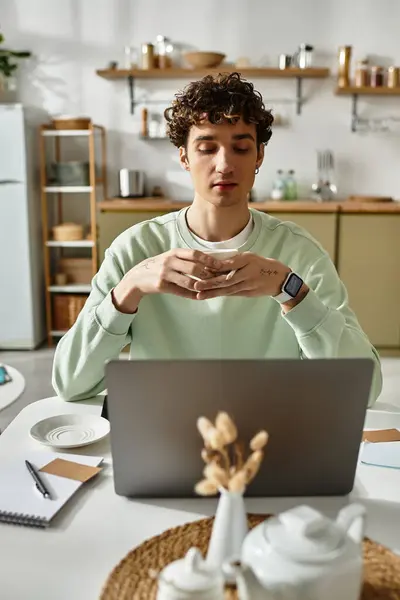 Un bel giovane uomo si concentra intensamente mentre lavora dal suo elegante home office in un ambiente accogliente appartamento. — Foto stock