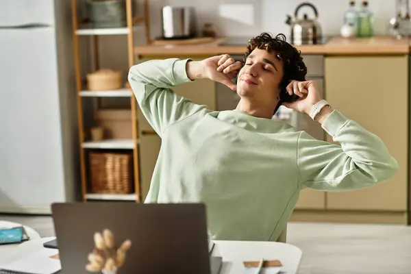 A young man relaxes with headphones, savoring music while working from home in a chic and modern apartment. — Stock Photo