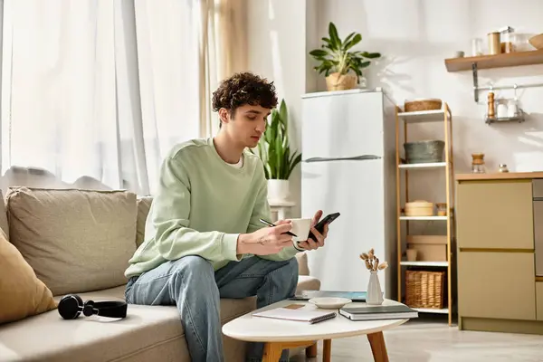 A young man with curly hair engages in work from his chic apartment, savoring coffee and ideas. — Stock Photo