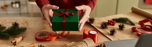 In a warm setting, a young man presents a beautifully wrapped Christmas gift amid festive decor. — Stock Photo