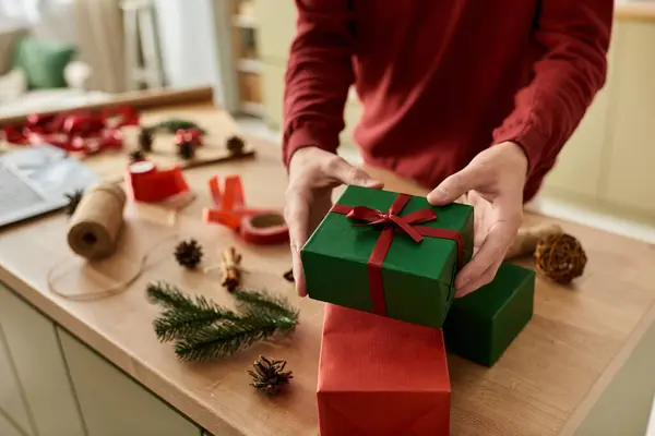 The young man prepares vibrant Christmas gifts surrounded by seasonal decorations and crafts. — Stock Photo