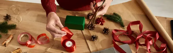 Un joven está envolviendo cuidadosamente los regalos con cintas vibrantes y agregando decoraciones de temporada.. - foto de stock