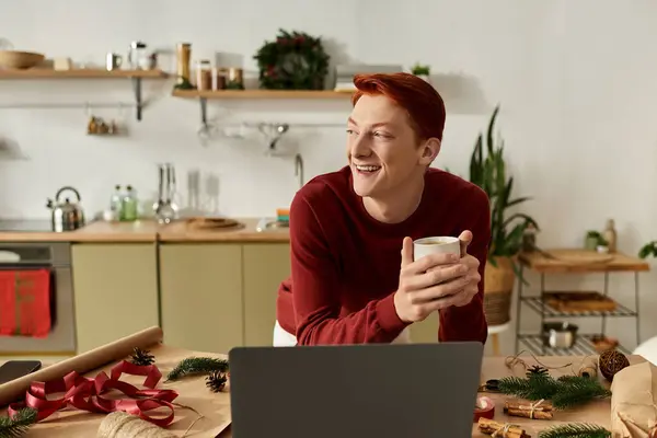 Ein junger Mann genießt ein warmes Getränk, während er sich auf eine fröhliche Weihnachtsfeier vorbereitet. — Stockfoto