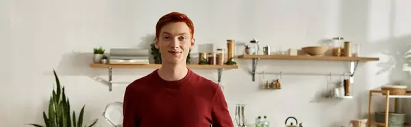 A young man with a warm smile stands in a bright and inviting kitchen, celebrating Christmas. — Stock Photo