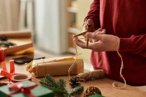 Un joven envuelve los regalos de Navidad con una precisión reflexiva y un espíritu alegre en casa. — Stock Photo