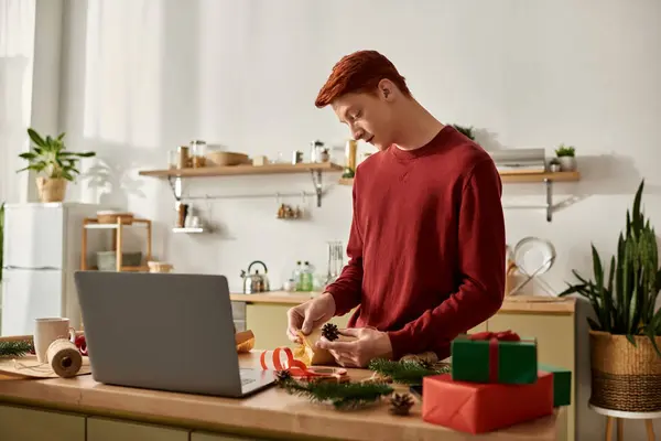 A young man is engaged in making Christmas decorations in his cozy kitchen setting. — Stock Photo