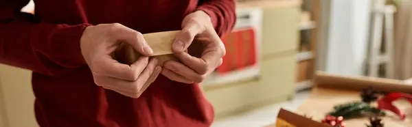 In a warm environment, a young man lovingly wraps a gift, embracing the holiday spirit. — Stock Photo