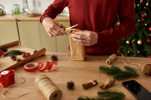 The young man meticulously wraps a Christmas gift, creating a festive atmosphere filled with cheer. — Stock Photo