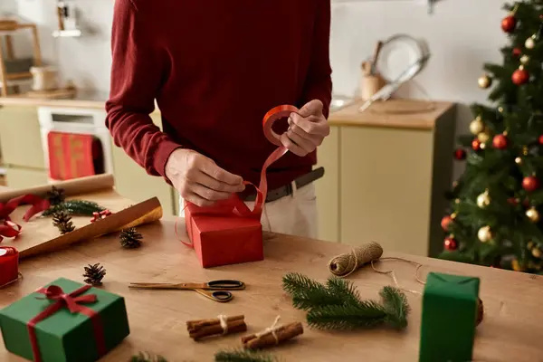 The young man carefully wraps festive gifts while surrounded by Christmas decorations and joy. — Stock Photo