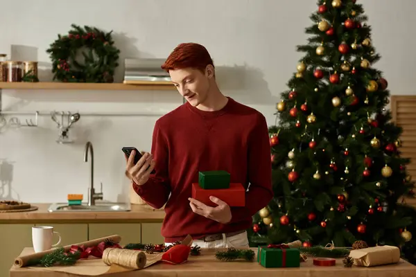 A young man in a red sweater admires Christmas gifts while surrounded by holiday decorations. — Stock Photo