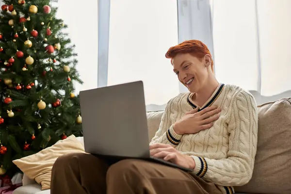 Um jovem alegre expressa alegria ao usar seu laptop em meio a decorações festivas. — Fotografia de Stock