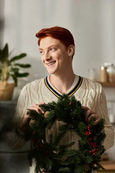 A cheerful young man displays a festive Christmas wreath, embodying the holiday spirit. — Stock Photo