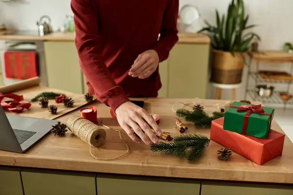 Ein junger Mann arrangiert Weihnachtsdekoration, während er in seiner warmen Küche Geschenke vorbereitet. — Stockfoto