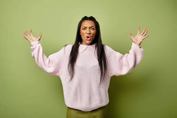 With a stylish sweater and relaxed pants, a young woman shows her emotions vividly in this setting. — Stock Photo