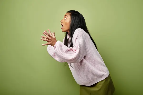 A young woman in trendy, warm clothes expresses excitement with lively gestures. — Stock Photo