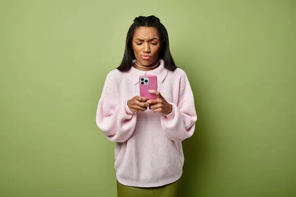 A young woman dressed in stylish warm clothing gazes at her phone, appearing puzzled or concerned. — Stock Photo