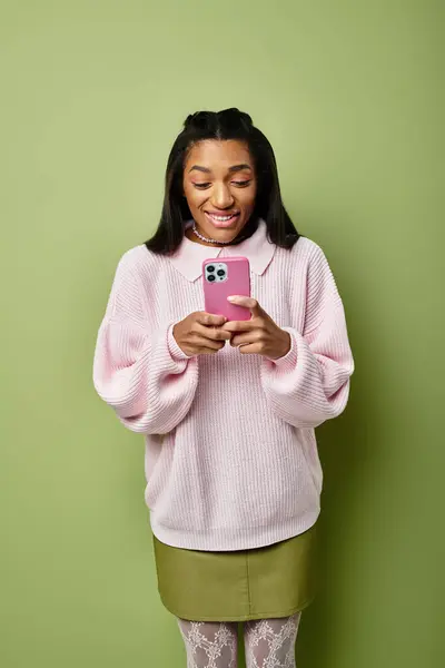 The young woman smiles brightly while texting, showcasing her autumn fashion and joyful spirit. — Stock Photo