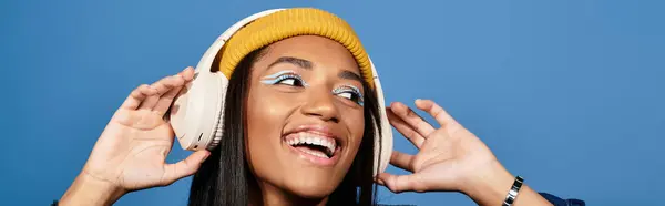 The young woman is joyfully listening to music with headphones, showcasing her trendy fall fashion. — Stock Photo