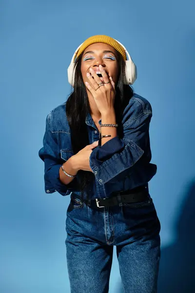 A young woman laughs while wearing stylish autumn clothing and headphones, embodying happiness. — Stock Photo