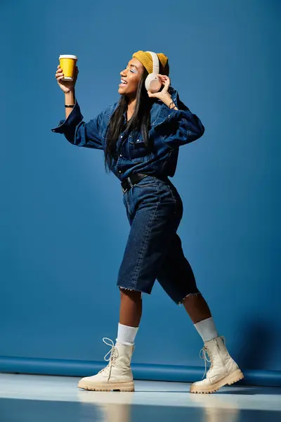 Une jeune femme en vêtements chauds d'automne marche joyeusement avec des tasses à café à la main. — Photo de stock