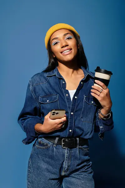 A young woman dressed in warm autumn layers enjoys her coffee with a cheerful smile. — Stock Photo
