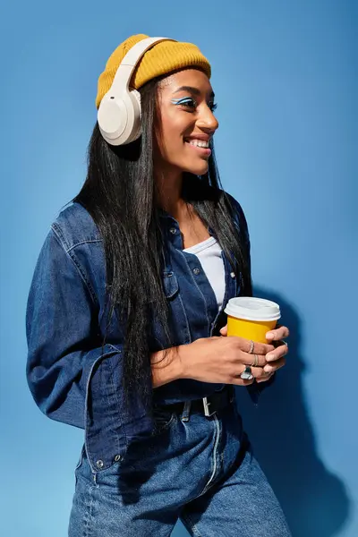 This young woman stands confidently, sipping a warm drink, showcasing her autumn fashion. — Stock Photo
