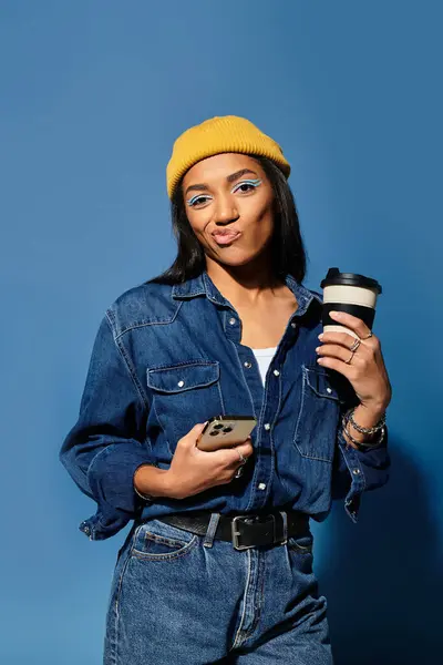 En traje de otoño de moda, la joven con estilo posa con café sobre un telón de fondo azul. — Stock Photo