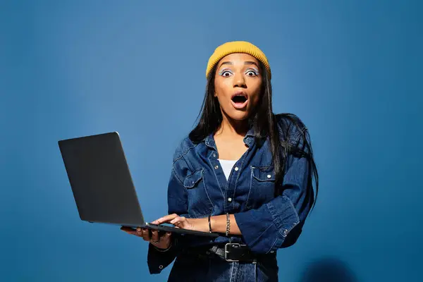 Uma jovem mulher em um conjunto de outono elegante expressa surpresa ao usar seu laptop. — Fotografia de Stock