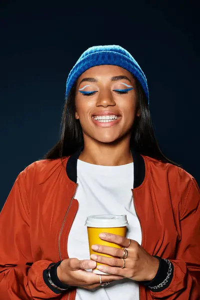 Vestita in elegante abbigliamento autunnale, una donna travi con gioia in possesso di una bevanda calda. — Foto stock
