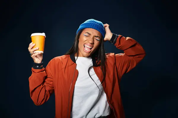 A young woman in cozy autumn gear happily holds a warm drink, celebrating the season. — Stock Photo