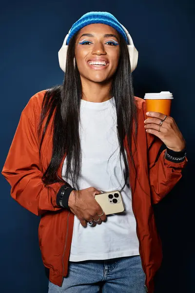 She smiles cheerfully while holding a coffee cup, dressed in warm autumn attire. — Stock Photo