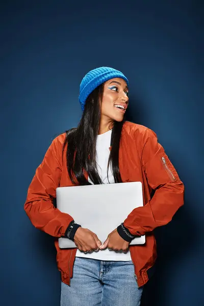 Una giovane donna in abiti autunno alla moda abbraccia gioiosamente il suo computer portatile, trasudando fascino e calore. — Foto stock