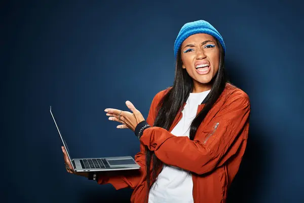 A stylish young woman in autumn clothing shows enthusiasm while engaging with her laptop. — Stock Photo